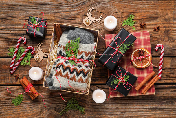 Örgü çoraplar, yanan mumlar ve ahşap arka planda Noel süsleri olan hediye kutusu. - Fotoğraf, Görsel