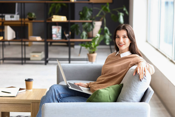 Schöne Geschäftsfrau arbeitet mit Laptop auf Sofa im Büro - Foto, Bild