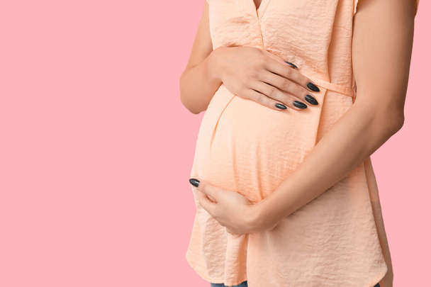 Mujer embarazada sobre fondo rosa, primer plano - Foto, imagen