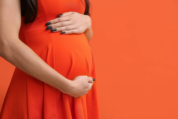 Mujer embarazada sobre fondo naranja, primer plano - Foto, Imagen