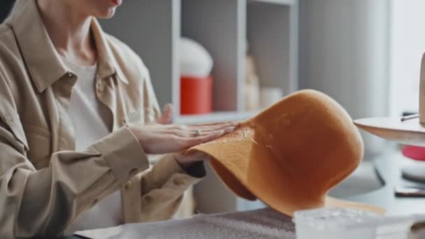 Döntés felfelé lövés női pincészet dolgozó ül a kézműves boltban bevonat új narancssárga kalap filccel merevebb - Felvétel, videó