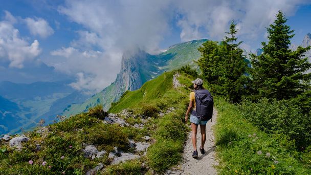women hiking in the Swiss Alps mountains during summer vacation with a backpack and hiking boots. woman walking on the Saxer Lucke path in Switzerland during summer - Photo, Image