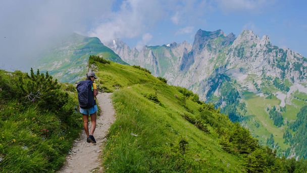 Yaz tatilinde sırt çantası ve yürüyüş botlarıyla İsviçre Alp Dağları 'nda yürüyüş yapan Asyalı kadınlar. İsviçre 'de yaz boyunca Sakson Lucke yolunda yürüyen bir kadın. - Fotoğraf, Görsel