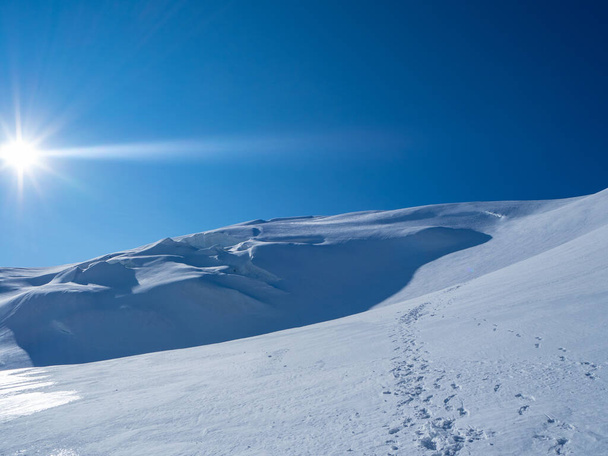 Солнечное утро на пике Стралхорн в Вале, Швейцария: Следы на снегу, ведущие к вершине. - Фото, изображение