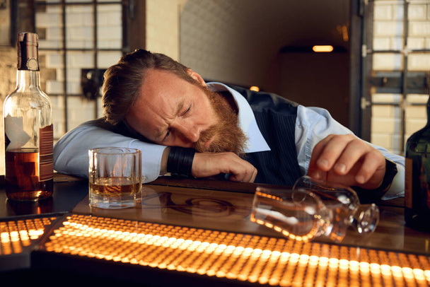 Boş bardağa dokunan depresif sarhoş adam umutsuzluk hissediyor. Alkol bağımlılığı, alkol sorunu - Fotoğraf, Görsel