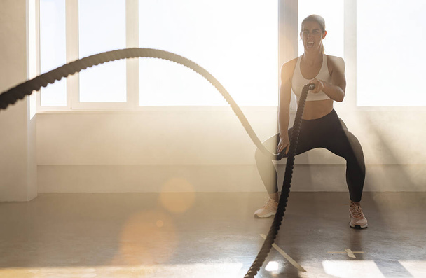Mulher com corda de batalha no ginásio de fitness de treinamento funcional - Foto, Imagem