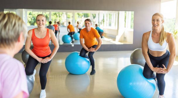 Ομάδα ανθρώπων στο γυμναστήριο που χρησιμοποιούν μπάλα για γυμναστική. Υγιεινός τρόπος ζωής, Άσκηση, Υγιεινή έννοια. - Φωτογραφία, εικόνα