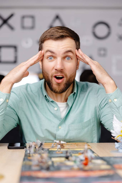 単独で戦略を実践しながらボードゲームピースを持つ男. 男はカードと数字でボードゲームをプレイし,異なる感情を表現する - 写真・画像