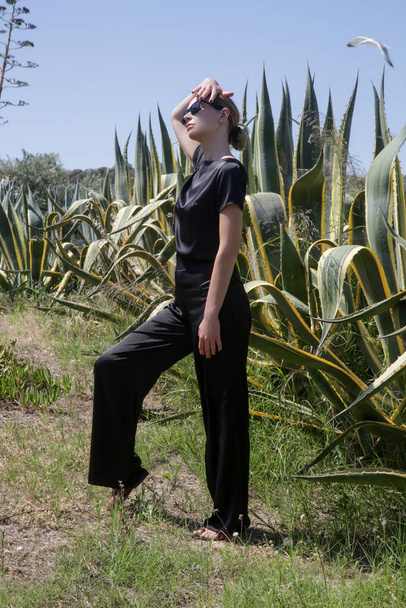 Outdoor-Mode Porträt einer Touristin in schwarzem Seidenoutfit während des Sommerurlaubs, Frühjahrssommerkollektion, schlichter Luxusstil - Foto, Bild