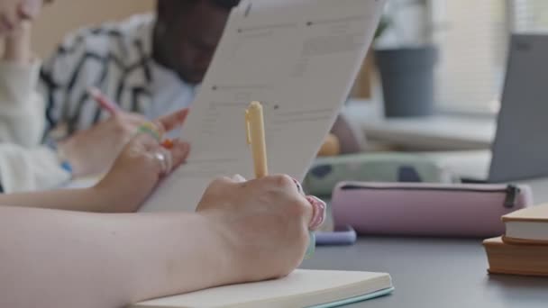 Közelkép a női diák kezét tartó papír teszt kérdéseket, és írja le a válaszokat a copybook míg átment vizsga a főiskolán - Felvétel, videó