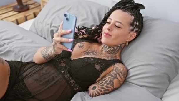 Itsevarma latino amputoitu nainen kutoma älypuhelimeen, näyttää seksikäs aamulla valossa, makaa makuuhuoneessa - Materiaali, video