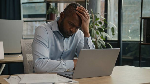 過労アフリカ系アメリカ人の成熟した男性オフィスでノートパソコンを作業疲れ目の緊張に苦しんで疲れ男性高齢者のビジネスマン痛み不快感頭痛片頭痛健康問題を感じる - 写真・画像