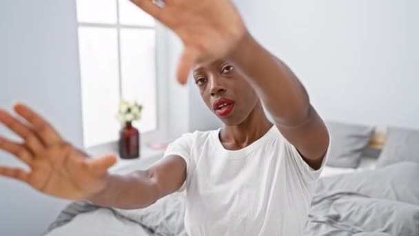 Perspective de caméra d'une femme afro-américaine joyeuse et créative allongée sur son lit, capturant un cadre unique avec ses mains et ses doigts dans une chambre confortable. - Séquence, vidéo