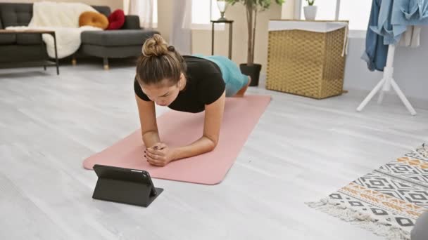 Sportliche junge hispanische Frau, die zu Hause ein ernsthaftes Online-Core-Workout absolviert und ihr Wohnzimmer mit ihrem Laptop in ein Fitness-Center verwandelt.  - Filmmaterial, Video