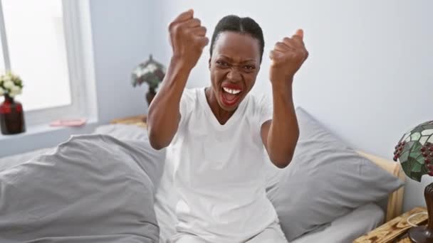 Furiosa mujer afroamericana acostada en la cama del dormitorio, loca de rabia agresiva, manos frustradas apretadas en los puños en medio de la ira - Imágenes, Vídeo