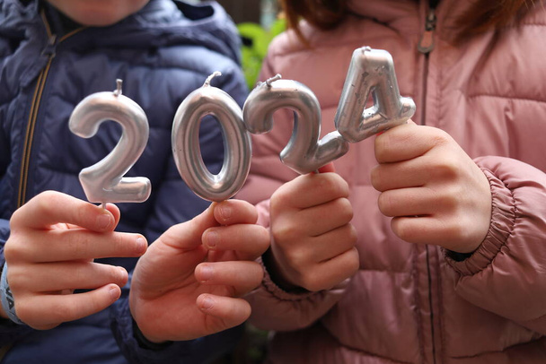 mãos de crianças segurando velas com números 2024. feliz ano novo. Horizontal. sem rosto - Foto, Imagem