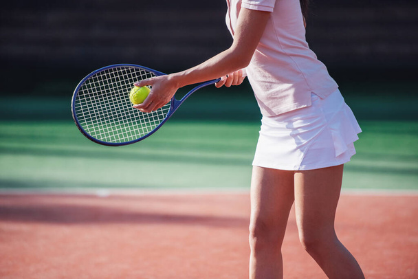 Rajattu kuva tyttö tilalla tennis maila pelatessaan tennistä kentällä ulkona
 - Valokuva, kuva