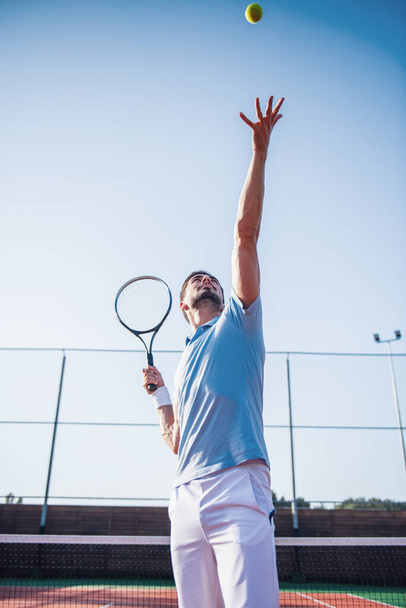 ハンサムな男は屋外のテニスコートでテニスします。 - 写真・画像