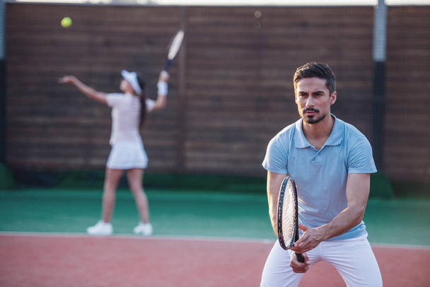 Beautiful young couple are playing tennis as a team on tennis court outdoors - Photo, Image