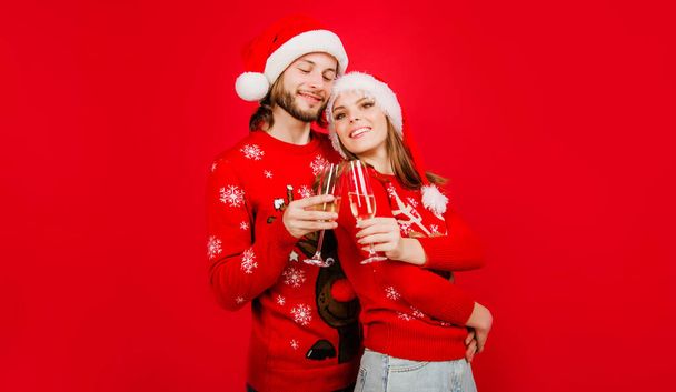 Beau couple en chapeaux de Père Noël avec des verres de champagne. Fête d'hiver. Joyeux Noël. Bonne année. Les relations. Couple de Noël en chandail Nouvel An boit du vin. Nouvelle fête de l'année - Photo, image