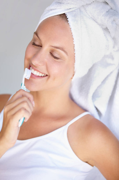 Жінка, чистить зуби і посміхається для здорового догляду у ванній кімнаті за гігієнічним ротом, зубною щіткою або здоров'ям. Жіноча особистість, зубна щітка і відбілювання рутини для ортодонтії, пероральне сяйво або блиск гінгівіту. - Фото, зображення