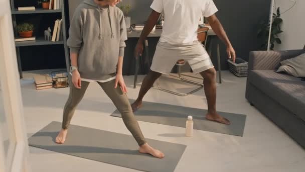 Volledig schot van Kaukasische vrouw in sportkleding onderwijzen Afro-Amerikaanse man yogas asanas - Video