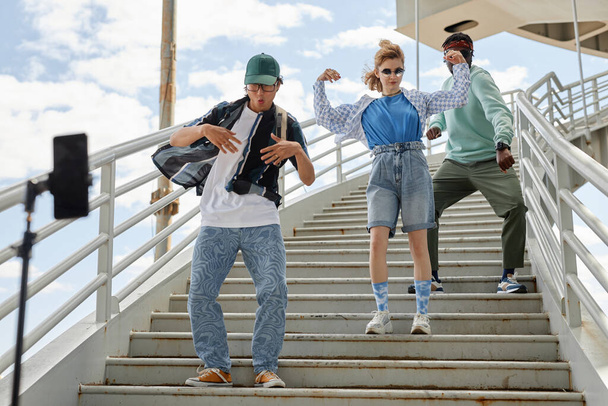 Διαφορετική ομάδα νέων που φορούν ρούχα street style χορεύοντας σε σκάλες σε εξωτερικούς χώρους στην αστική περιοχή - Φωτογραφία, εικόνα