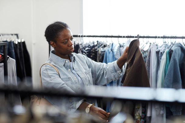 Vita su ritratto di nero giovane donna guardando i vestiti nel negozio di risparmio - Foto, immagini