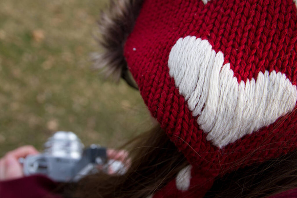 Cozy Love: Μια γυναίκα φωτογράφος στο Fort Wayne της Ιντιάνα, αιχμαλωτίζει τη μαγεία του χειμώνα με ένα κόκκινο πλεκτό σκουφάκι διακοσμημένο με σχέδιο καρδιάς, που συμβολίζει τη ζεστασιά και τη στοργή. Αγκαλιάστε τη χαρά του - Φωτογραφία, εικόνα