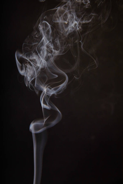 Remolinos cautivadores de delicado humo blanco sobre un fondo oscuro, evocando misterio y elegancia. Una representación fascinante de la transformación y la naturaleza fugaz del tiempo. Perfecto para la salud y - Foto, imagen