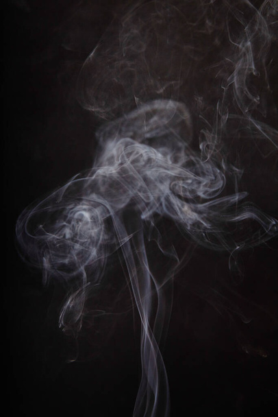 Remolinos fascinantes de humo etéreo sobre un fondo oscuro, capturando el misterio y la fluidez del movimiento. Perfecto para conceptos como la creatividad, el pensamiento y la naturaleza fugaz de los momentos. - Foto, Imagen