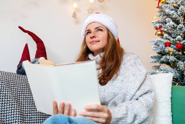 Felnőtt nő Santa kalap olvasás mese könyv, fantáziák és álmok a karácsonyi ünnepek. - Fotó, kép