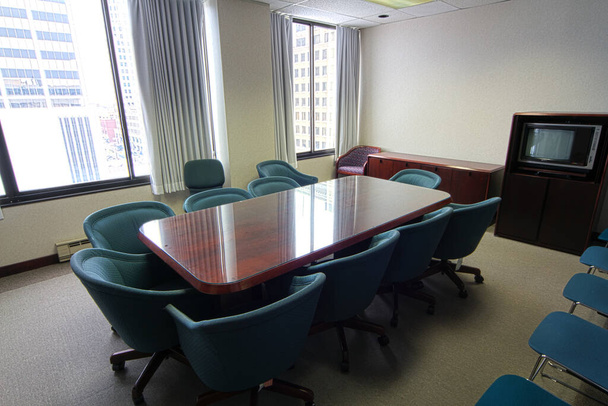 Parlak ahşap konferans masası, deniz mavisi ofis sandalyeleri ve Fort Wayne, Indiana 'daki eski tarz televizyon dolabı olan profesyonel şirket toplantı odası.. - Fotoğraf, Görsel