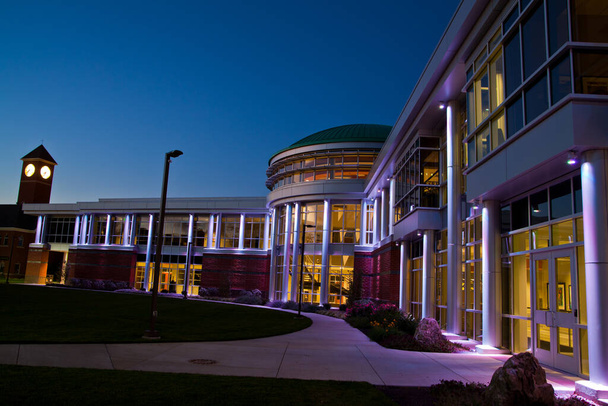 Современное образовательное здание светится архитектурным освещением во время синего часа в Форт-Уэйн, Индиана. - Фото, изображение