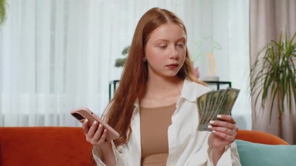 Suunnittelen perheen budjettia. Hymyilevä teini tyttö laskee rahaa käteisellä, käyttää älypuhelinta laskea kotimaan laskuja kotona huoneessa. Iloinen lapsi tyytyväinen tuloihin ja säästää rahaa suunniteltuun lomaan, lahjoihin - Materiaali, video