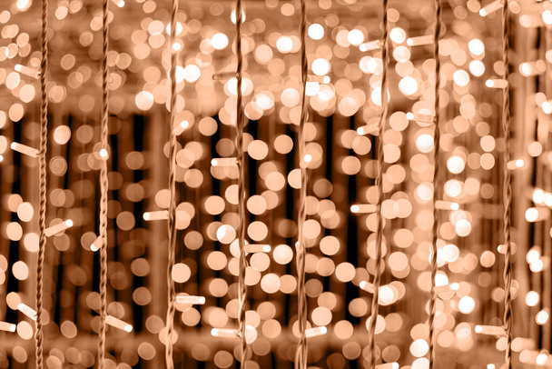 Perzikfuzz is de kleur van het jaar 2024. Warme gouden lichten creëren een magisch bokeh effect. Kerstverlichting - Foto, afbeelding