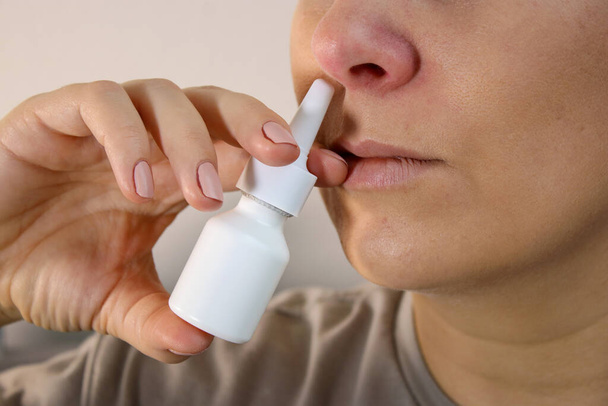 Primer plano de la mujer enferma con la nariz roja usando un aerosol nasal, fondo borroso con espacio para copiar - Foto, Imagen