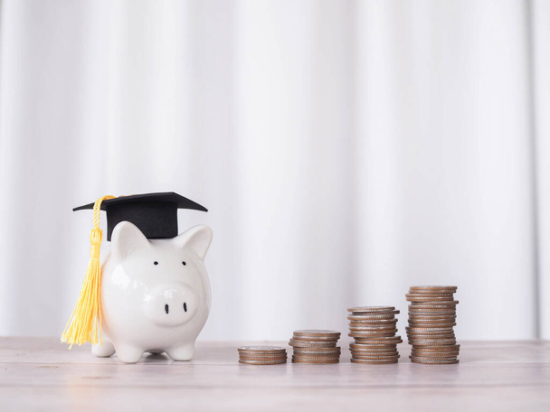 Hucha con sombrero de graduación y pila de monedas. El concepto de ahorrar dinero para la educación, préstamo estudiantil, becas, tasas de matrícula en el futuro - Foto, Imagen