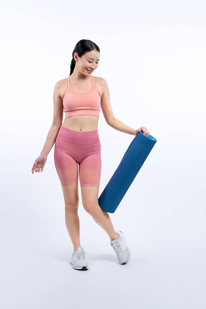 Молода приваблива азіатська жінка портрет в спортивному одязі з тренувальним килимком. Здорові фізичні вправи і тренування рутинного способу життя концепції. Студійний знімок ізольований фон. Яскравий - Фото, зображення