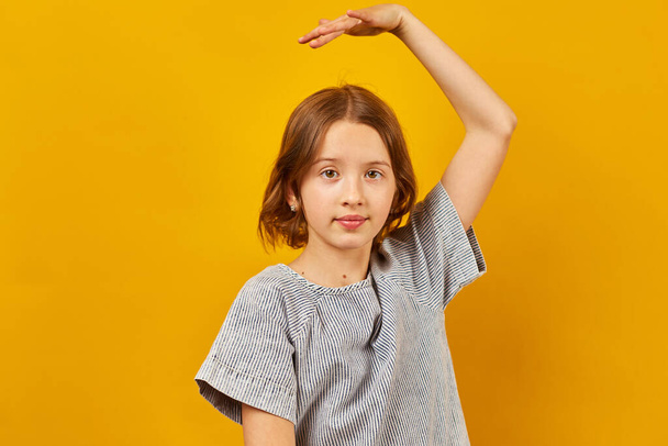 Feliz chica adolescente bailando sobre fondo de estudio amarillo, concepto de estilo de vida positivo. - Foto, Imagen
