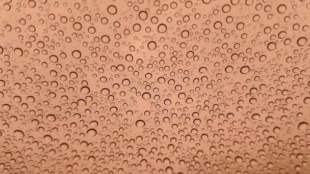 Imagen abstracta de gotas de lluvia sobre vidrio. Imagen tonificada en color Melocotón Fuzz del año 2024. Nuevo color de moda. Vista superior. Vista de gotas abstractas - Foto, imagen