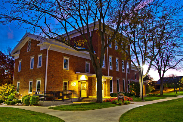 Serene twilight at a classic brick community center in Fort Wayne, Indiana. Warm lighting illuminates the traditional architecture. Perfect for marketing local services and highlighting community - Photo, Image