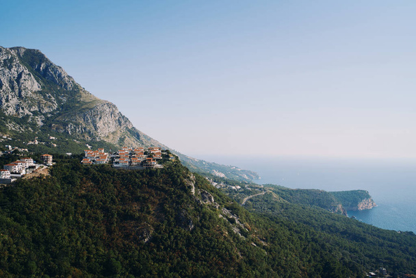 Pueblo rico en la montaña Doma con vistas a la bahía y la isla de Sveti Stefan. Montenegro. Foto de alta calidad - Foto, Imagen