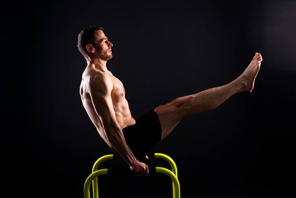 Gymnaste masculin exécutant handstand sur un bar parallèle, plan studio - Photo, image