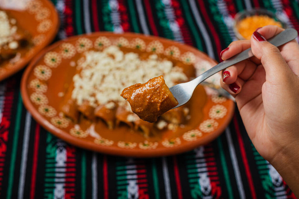 Persona comiendo enchiladas con pipián rojo. Comida típica mexicana. - Foto, Imagen