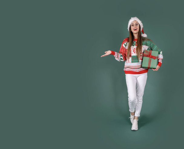 Holding lahjapaketti, koko kehon näkymä innoissaan melko brunette Santa nainen tilalla lahjapaketti. Ostokset talvilomalle, juhlii hyvää joulukonsepti-ideaa. Erillinen vihreä taustakopiotila. - Valokuva, kuva