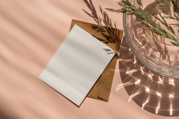Blank paper card and envelope mockup with copy space on peach fuzz color background with aesthetic natural sun light shadows. Feminine business brand template in trendy color 2024. - Photo, Image
