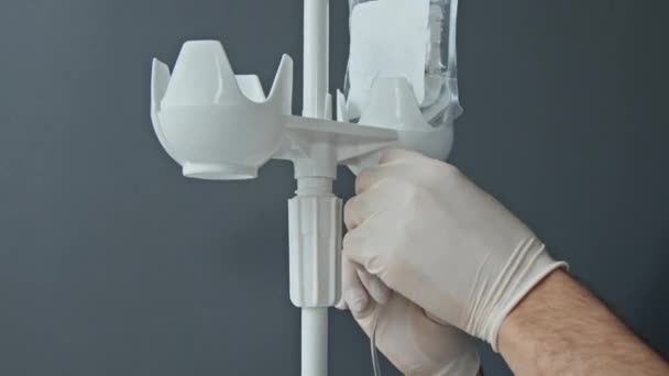 Gros plan mise au point sélective des mains d'une infirmière masculine méconnaissable préparant un pôle IV pour son patient - Séquence, vidéo