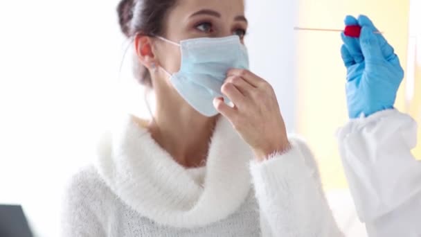 Dokter laboratoriumassistent in beschermende pak neemt uitstrijkje van de neus van zieke patiënt thuis. Laboratoriumtests op het concept coronavirus - Video