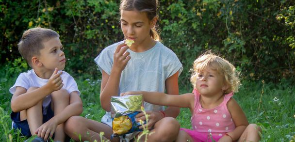 щасливі діти їдять чіпси в парку. Вибірковий фокус. дитина - Фото, зображення